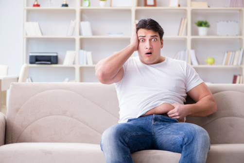 Shocked man holding his belly fat with one hand